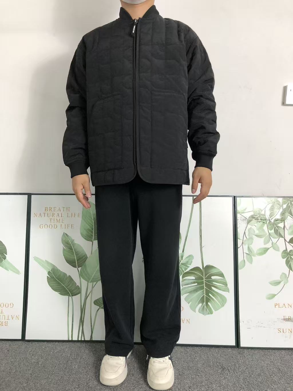 Black quilted liner jacket worn with black trousers, front